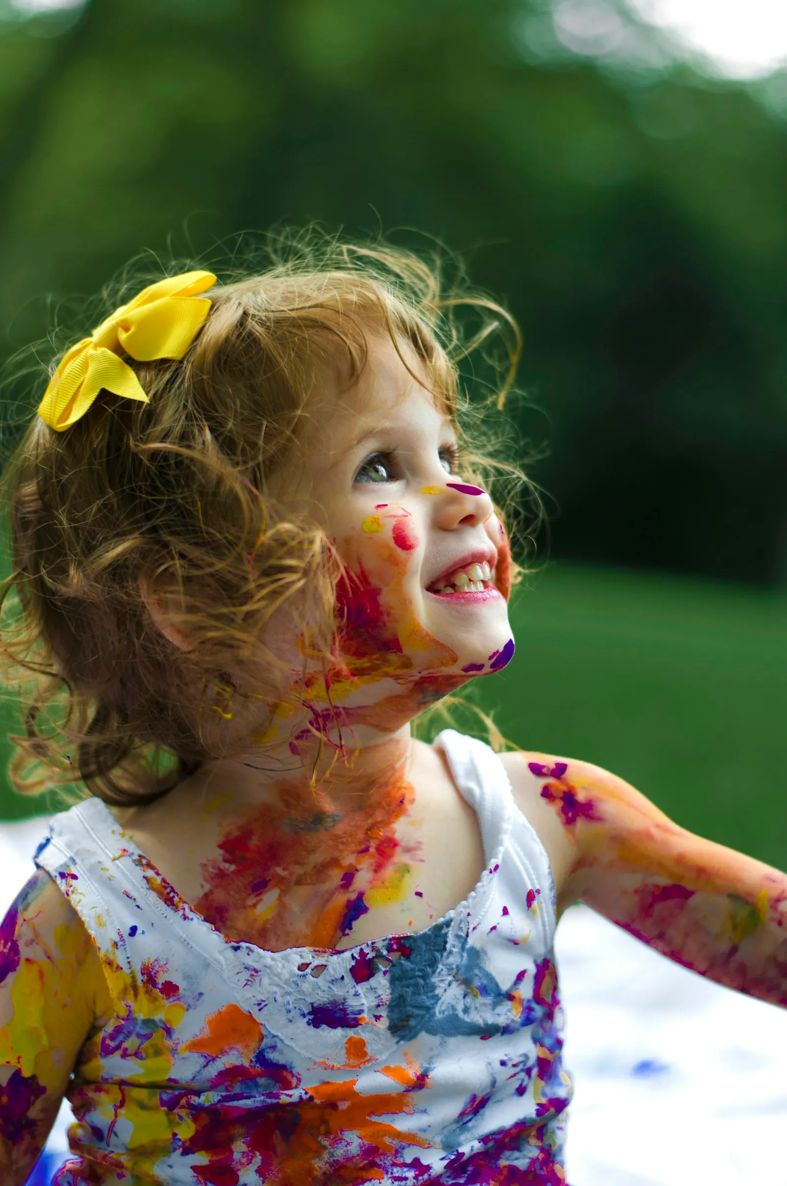A smiling little girl with colourful paint on her face after art time