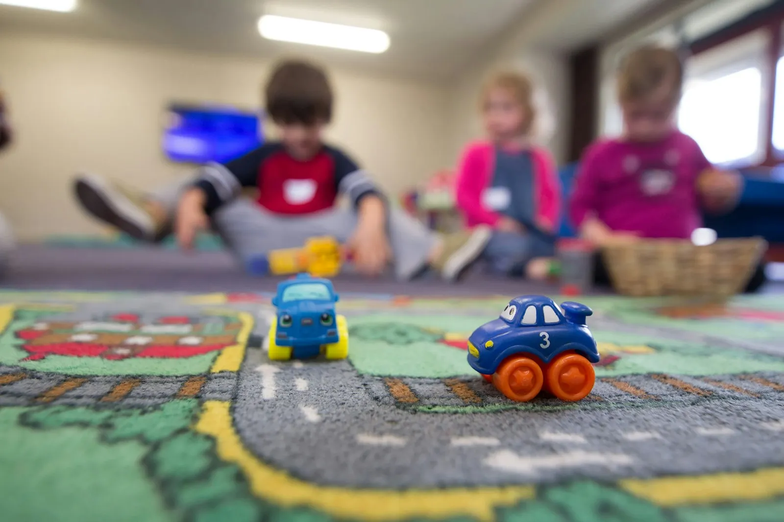 Young children playing with toy cars on a play mat